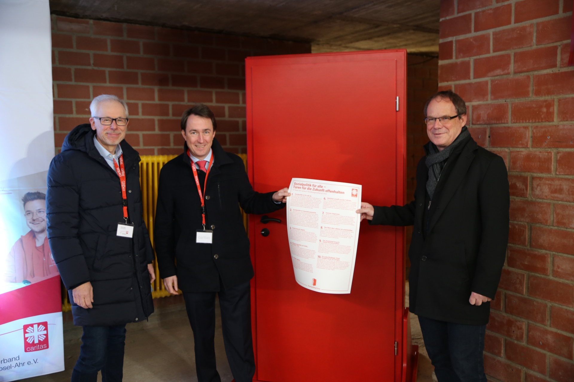 „Türen für die Zukunft offenhalten“: Richard Stahl und Christian von Wichelhaus (l.) bringen gemeinsam mit Dr. Oliver Müller (r.), symbolisch 10 Thesen der Caritas im Bundestagswahlkampf an eine Tür an.